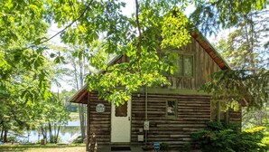 A rustic cabin with a wooden exterior, a front porch, and a sign indicating it is a cabin. - Lakes End Log Cabin on Lake Wicwas! (Meredith)