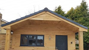 Eine kleine Holzhütte mit Satteldach, einer Haustür und einem Fenster.