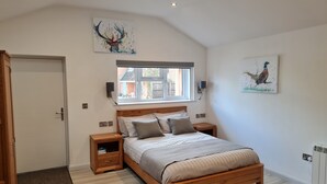 Ein Schlafzimmer mit einem hölzernen Bett, einem Fenster, zwei Nachttischen, einer Tür und zwei Wandleuchten.