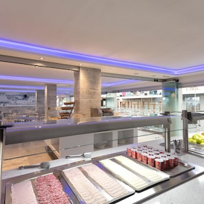 En buffet med forskellige retter og et siddeområde i baggrunden.