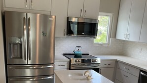 Une cuisine moderne dotée d’appareils électroménagers en acier inoxydable, de meubles blancs et d’un plan de travail en marbre.