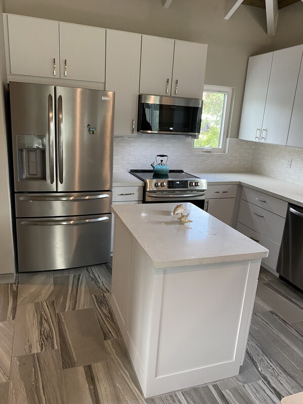 Enjoy cooking in this well-equipped kitchen with a refrigerator, microwave, and oven, complemented by a central island and tile backsplash.