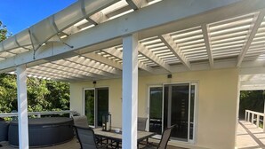 Une terrasse extérieure couverte avec une piscine, un espace salon et une pergola offrant de l’ombre.