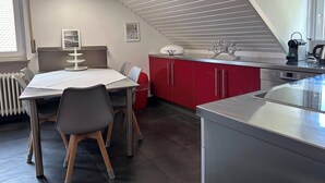 A modern kitchen with a dining area, red cabinets, and a white ceiling.