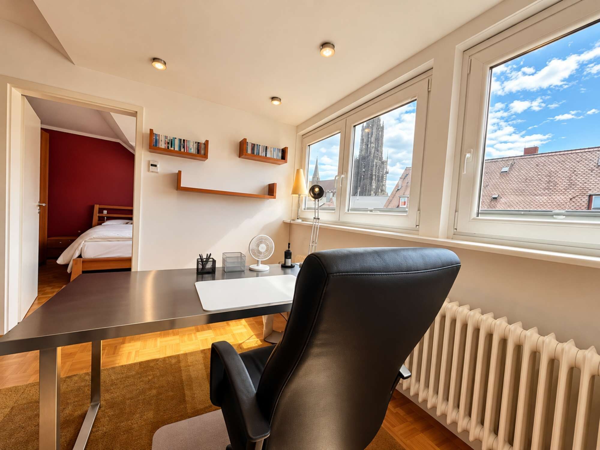 Ein modernes Zimmer mit Schreibtisch, Stuhl und Bücherregalen.