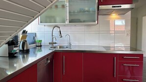 A modern kitchen with red cabinets, a stainless steel sink, and a built-in oven.