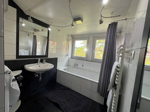 A modern bathroom with a bathtub, a sink, and a shower.