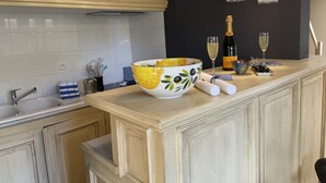 A kitchen with a large bowl, a wine bottle, and glasses on the counter. - Paradis de Provence (Le Pin)