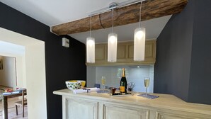 A kitchen with a bar area, wooden ceiling beams, and a tiled backsplash. - Paradis de Provence (Le Pin)