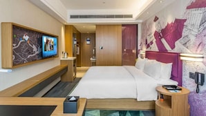 Een hotelkamer met een groot bed, een bureau, een televisie en een aan de muur bevestigd telefoontoestel.