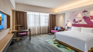 Een hotelkamer met een bed, een bureau, een stoel, een televisie en een groot raam met gordijnen.