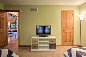 A room with a television on a white entertainment center, a wooden door, and a lamp.