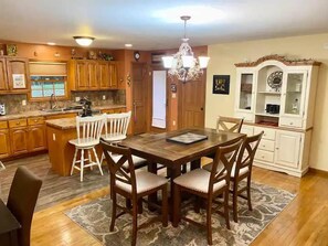 A dining area with a wooden table and chairs, a chandelier, and wooden cabinets.