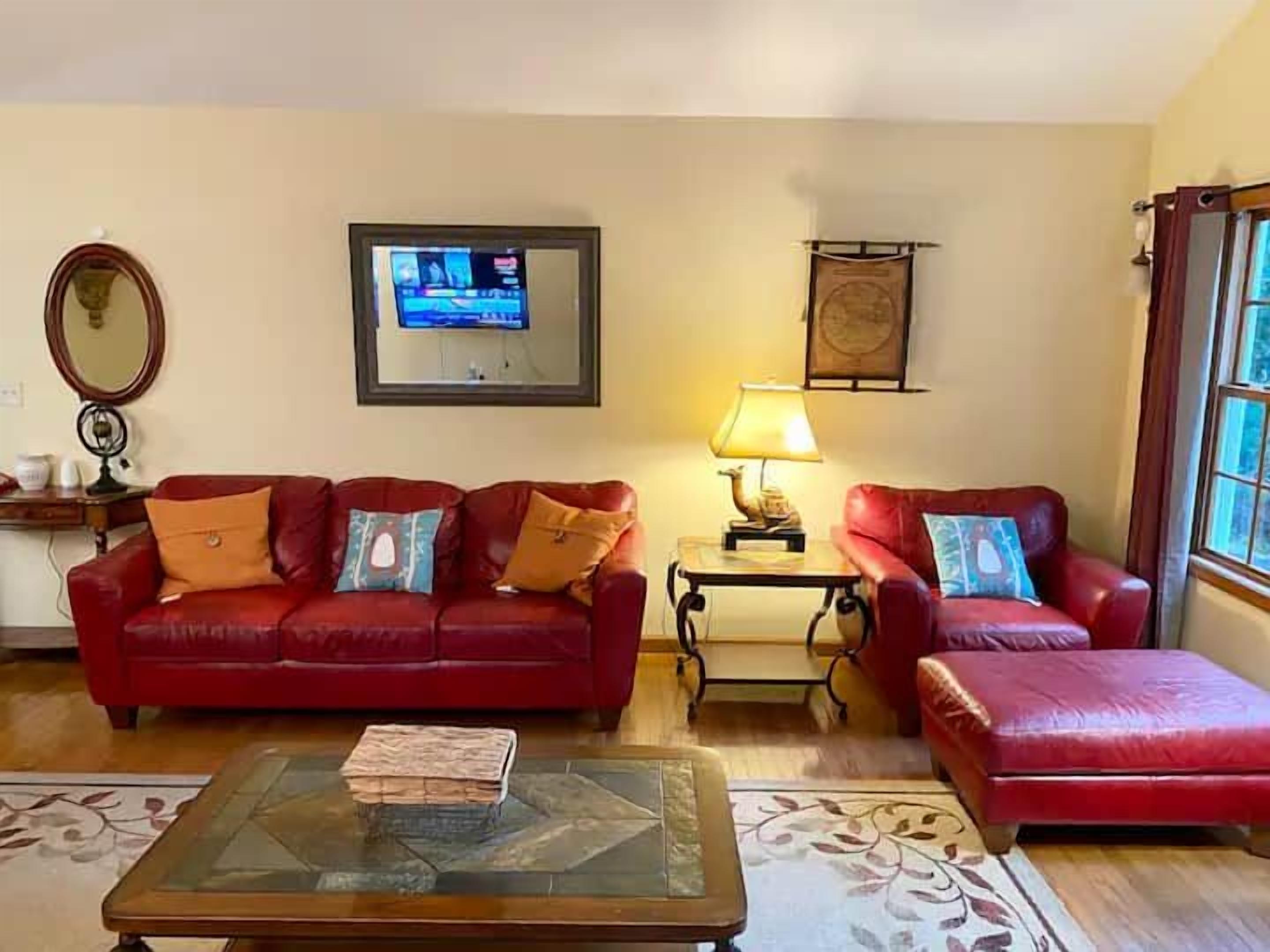 A living room with a red sofa, a coffee table, a TV, a lamp, and a window.