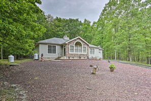 Set amidst a wooded area, this charming house features a two-story facade, a front porch, and a decorative windmill.