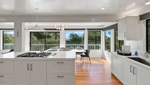 A modern kitchen with a central island, large windows, and a dining area with a view. - Sunset Villa: Upscale Three Bedroom Three Bath with Ocean Views (Pebble Beach)