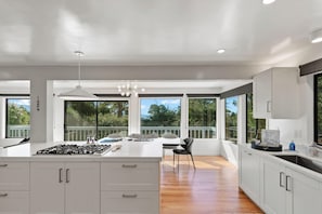 Una cocina moderna con una isla central, ventanas amplias y un comedor con vistas.