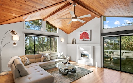 A modern living room with a sectional sofa, a glass coffee table, and a fireplace.