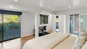 Un dormitorio moderno con una cama grande, un escritorio y vistas al jardín.