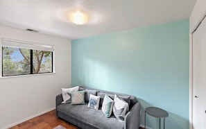 A living room with a grey sofa, a small round table, and a window with a view of trees.