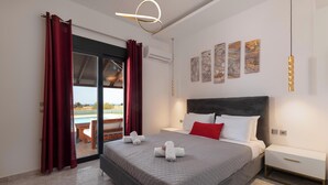 A bedroom with a bed, a nightstand, a view of the pool, and artwork on the wall. - Elysian Villa in Afantou (Αφάντου)