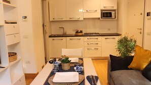 Une cuisine compacte avec des meubles blancs, un four à micro-ondes et un coin repas avec une table dressée pour deux personnes.