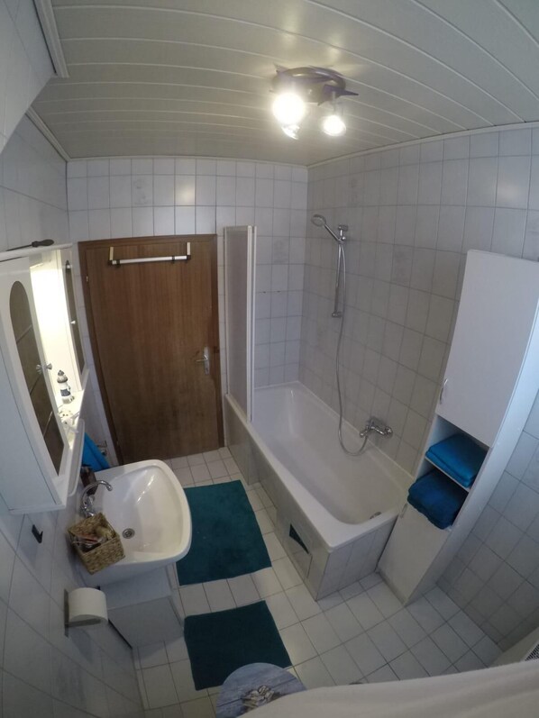 Un baño con bañera, ducha, lavamanos y espejo.
