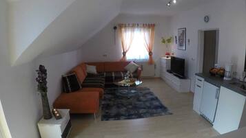 Ein kompakter Wohnbereich mit Sofa, Couchtisch und Küchenzeile.