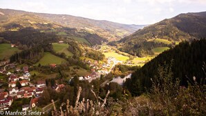 A valley with a small town surrounded by hills and forests.