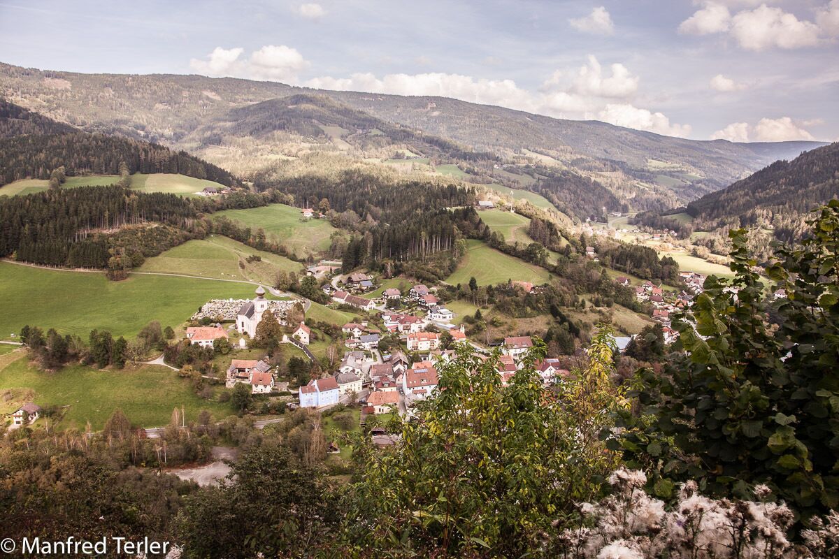 Un pueblo enclavado en un valle, con casas y abundante vegetación.