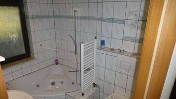 Een badkamer met een bad, toilet en een douchehoek.