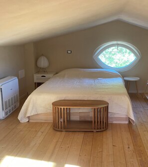 Une chambre avec un lit, une petite table, un radiateur et une fenêtre.