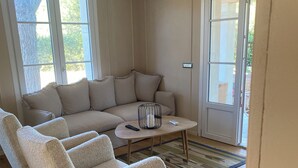 A living room with a beige sofa, a coffee table, and a white armchair. - Casa Riservata Immersa Nella Natura con Spiaggia Raggiungibile a Piedi (Toscana)