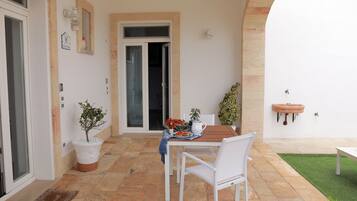 A patio area with a table and chairs, a potted plant, and a small sink.