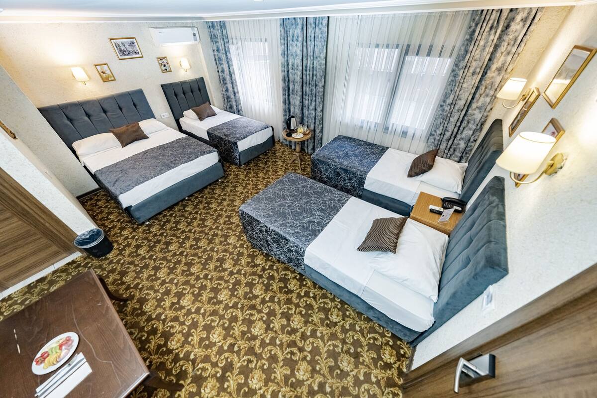 A hotel room with two beds, a small table, and a seating area.