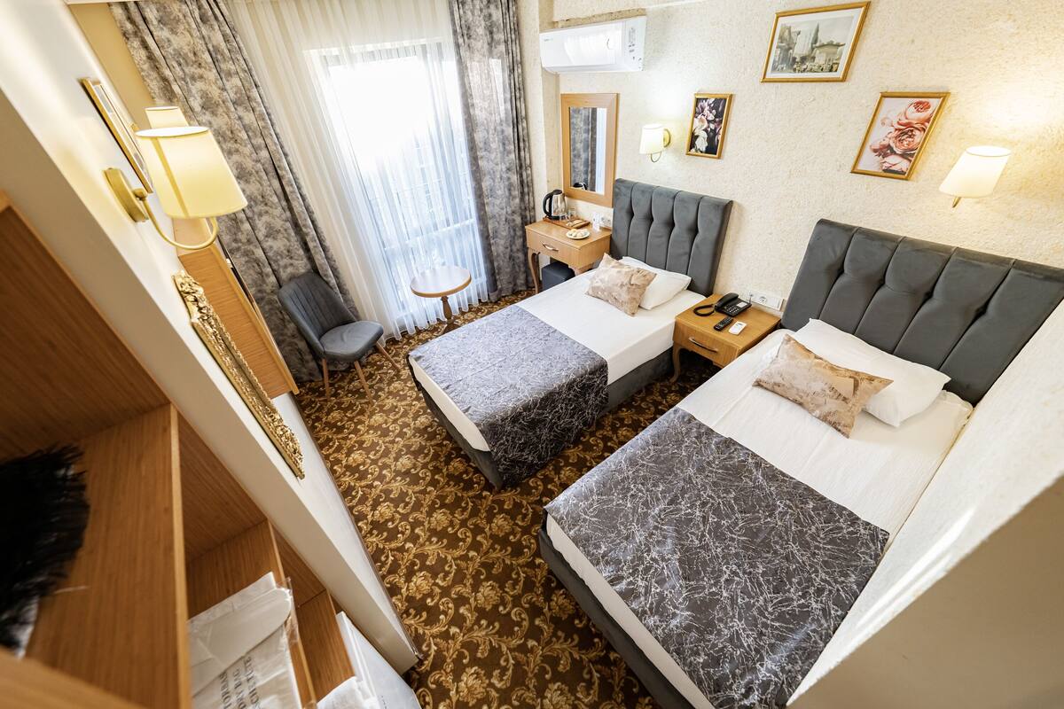 A hotel room with two beds, a desk, a chair, a wardrobe, and a bathroom.
