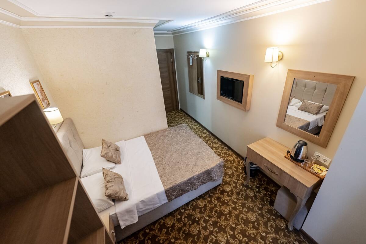 A hotel room with a bed, a desk, a mirror, and a small bathroom.