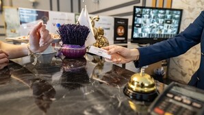 A hotel reception desk with a black marble surface, a gold bell, and a computer monitor displaying multiple screens. - Hamit Hotel Kizilay (Ankara)