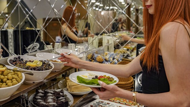 A buffet with various food items and a person serving themselves. - Hamit Hotel Kizilay (Ankara)