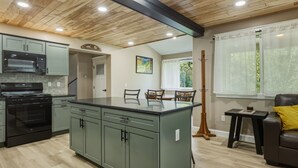 A kitchen with a central island, built-in appliances, and a dining area with chairs.