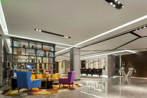 A modern lobby with a reception desk, seating area, and decorative shelving.