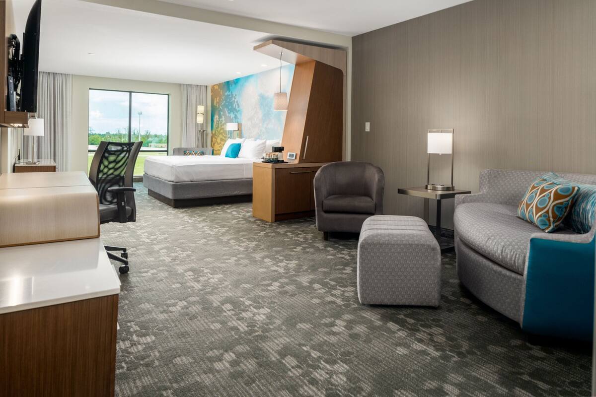 A hotel room with a bed, a sofa, a desk, and a chair.
