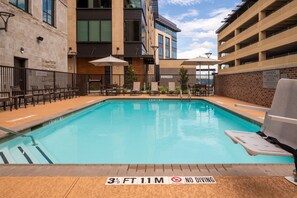 An outdoor swimming pool with a no diving sign, surrounded by outdoor seating and a brick wall. - Courtyard by Marriott Houston Northeast (Houston)