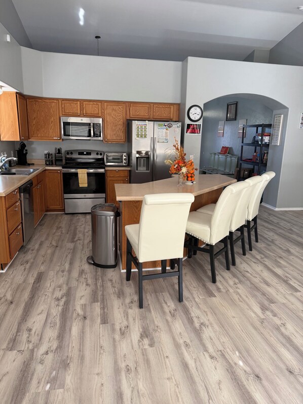 A modern kitchen with wooden cabinets, stainless steel appliances, and a dining area with a table and chairs.