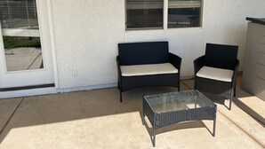A patio area with two wicker chairs and a glass table. - Sheppard 3bd1ba FtHuaSierraVista baby-massage (Sierra Vista)