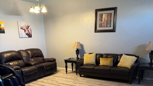 A living room with a brown leather sofa, a coffee table, and a lamp. - Sheppard 3bd1ba FtHuaSierraVista baby-massage (Sierra Vista)