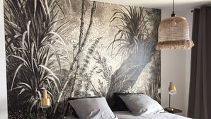 A bedroom with a large wall mural, a bed with white bedding, a hanging light fixture, and a small table with a lamp. - Bastia : Apartment facing the sea, 2 beaches nearby  (San-Martino-di-Lota)