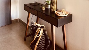 A dark wooden console table with a round mirror, a straw hat, a vase with dried plants, a small potted plant, and a tray with a notebook and pen. - Bastia : Apartment facing the sea, 2 beaches nearby  (San-Martino-di-Lota)
