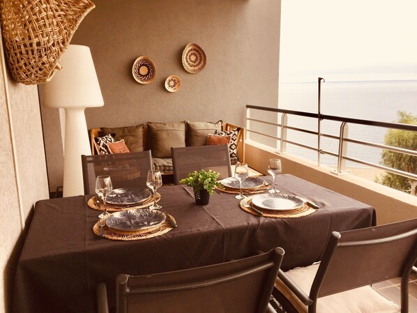 A dining table set for two with a view of the sea.
