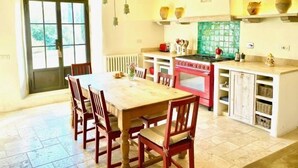 A kitchen with a dining table and chairs, a red stove, and a window with a view of greenery. - Spectacular views from this villa for 8 in Valdorcia. Private Pool. (Sarteano)